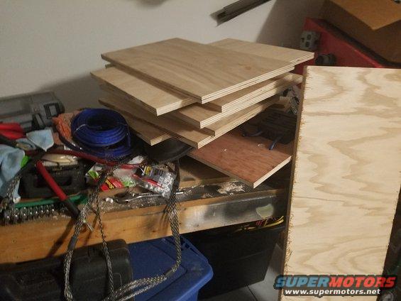 Stack of plywood sheets on a workbench with tools and wiring