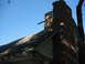 1966 Ford Bronco - A close-up view of a damaged brick chimney and a weathered roof under a bright blue sky.
