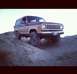 1987 Ford Bronco II - A two-tone 1987 Ford Bronco II navigates a dirt incline under a clear sky.