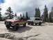 1987 Ford Bronco II - Two modified SUVs navigate a rocky, off-road terrain under a cloudy sky.