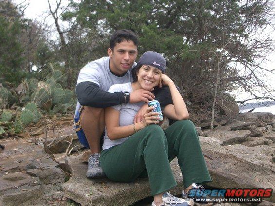 Couple sitting on rocks near water, man has arm around woman