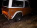 1969 Ford Bronco - Rear view of an orange and white Ford Bronco parked outdoors in the dark.
