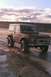 1969 Ford Bronco - A classic red Ford Bronco navigates a wet, muddy terrain under a cloudy sky.