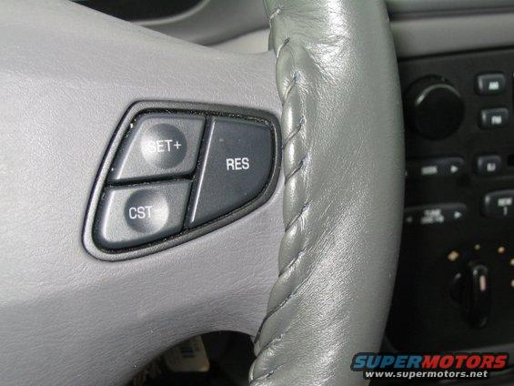 Gray steering wheel with SET+, RES, and CST buttons; part of the dashboard is visible