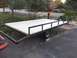 1986 Argo Response - A utility trailer with a newly installed wooden deck and metal side rails is parked on a paved surface.