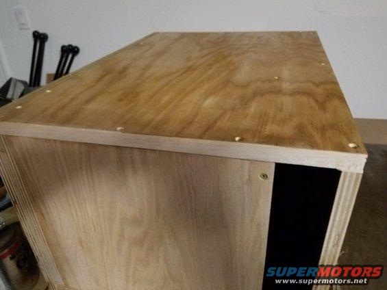 plywood box with black interior opening, some screws visible