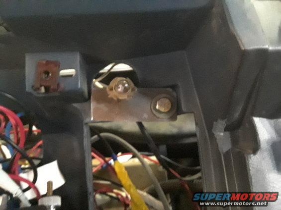 Dashboard interior with exposed wiring, a metal bracket, and a light bulb socket