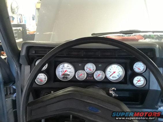 Custom gauge cluster with multiple aftermarket gauges including tachometer and speedometer