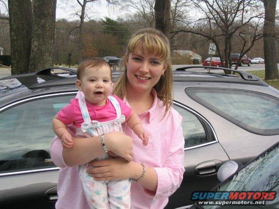 Dark station wagon side view, woman and baby in foreground