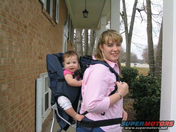 Woman with a baby in a backpack carrier on a porch