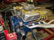 1970 Ford Torino - A blue Ford V8 engine with silver valve covers and chrome headers is shown in a workshop setting.