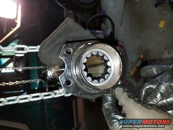 Splined shaft hub with roller bearings, held by gloved hands, with chains in background