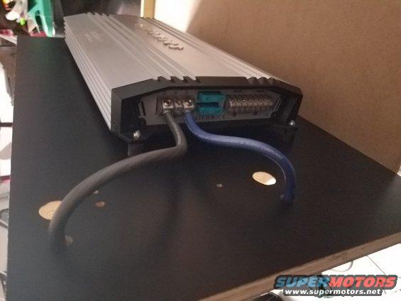 Car amplifier with power and speaker wires connected to terminals