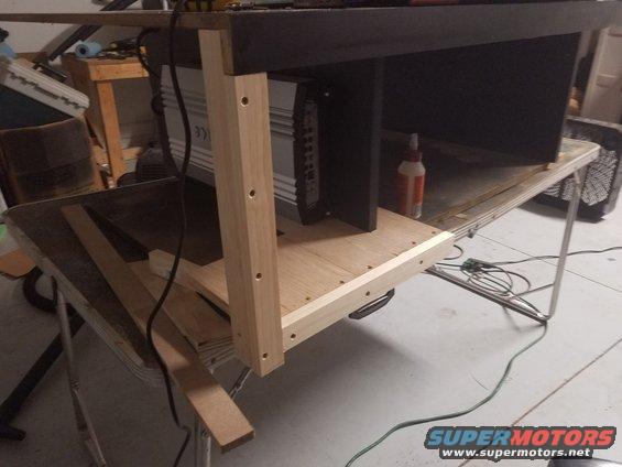 car amplifier mounted in a wooden enclosure on a workbench
