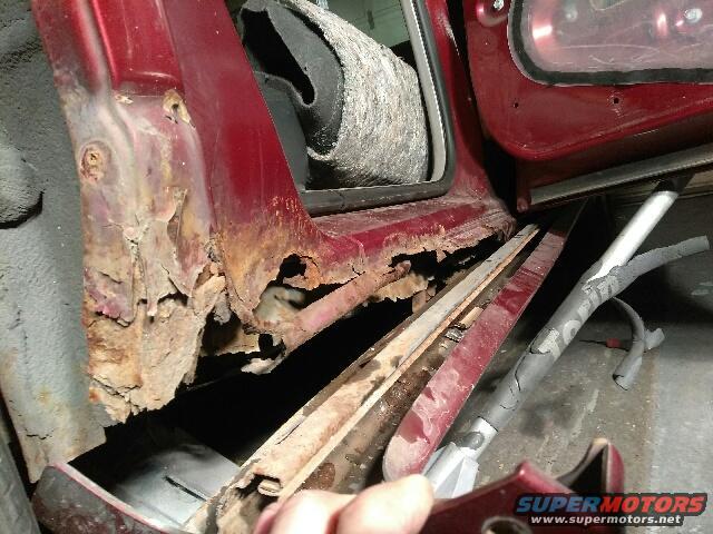 severely rusted red car door sill with interior visible
