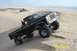 2000 Ford F-450 - A modified black pickup truck navigates sandy terrain with its large tires.