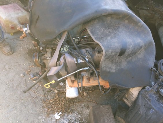 Engine with a black cover over it, sitting on the ground next to a gas can