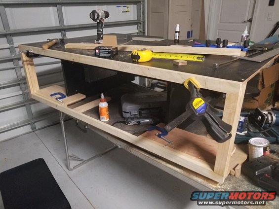 Workbench with drill, tape measure, clamps, and wood pieces