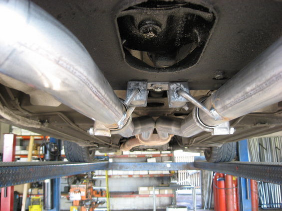 Underside view of a car's dual exhaust system with custom piping and hangers