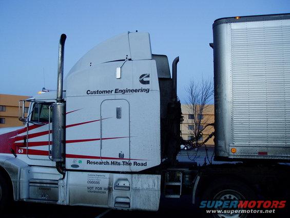 White semi-truck with red stripes and a silver trailer, side view. Text on truck reads "Customer Engineering" and "Research Hits The Road"