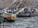 2000 Ford F-450 - Several off-road vehicles are mired in deep mud, with people observing the scene.