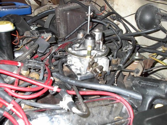 Engine bay close-up showing carburetor and red spark plug wires
