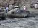 2000 Ford F-450 - Several trucks are stuck in thick mud, with one pickup truck tilted at an angle.