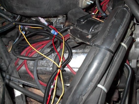 Close-up of a vehicle's engine wiring harness with red and yellow wires
