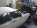 1987 Jaguar XJ6 - A person works on the engine of a white sedan in a garage.
