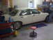 1987 Jaguar XJ6 - A person works on the engine of a white 1987 Jaguar XJ6 sedan parked in a garage.