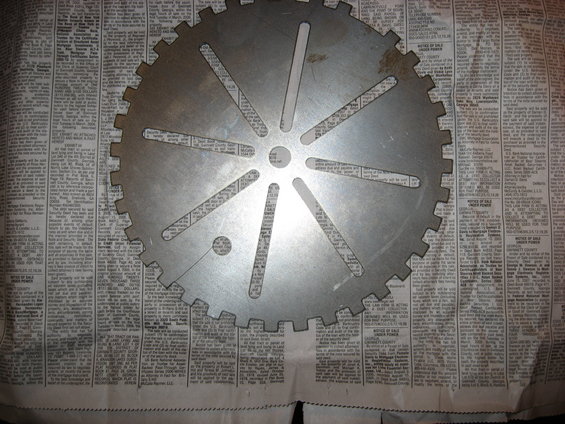 Metal gear with radial slots and teeth, placed on newspaper