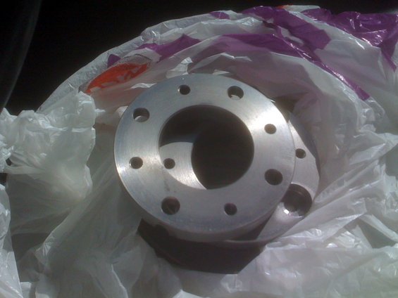 Metal flange with eight bolt holes, wrapped in plastic bags
