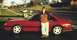 1986 Ford Mustang - A person poses with a red 1986 Ford Mustang coupe parked on a residential street.