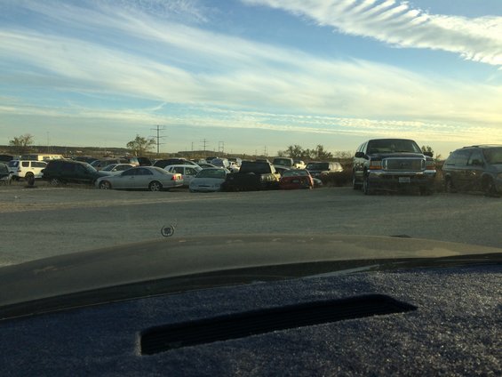 Junkyard scene with scattered vehicles and buildings under a cloudy sky