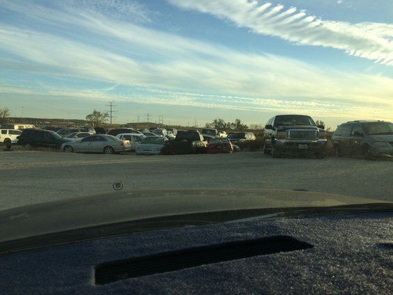 Junkyard scene with various cars and trucks under a cloudy sky