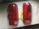 1989 Ford Bronco - Pair of red tail lights shown, one still in protective plastic packaging.