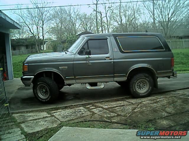 1989 Ford Bronco parked on a concrete driveway next to a garage