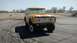 1971 Ford Bronco - A yellow 1971 Ford Bronco with white racing stripes sits on a cracked asphalt surface under a clear sky.