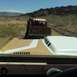 1971 Ford Bronco - View from inside a 1971 Ford Bronco, looking at its hood scoop and a pickup truck with a striped canopy in the distance.