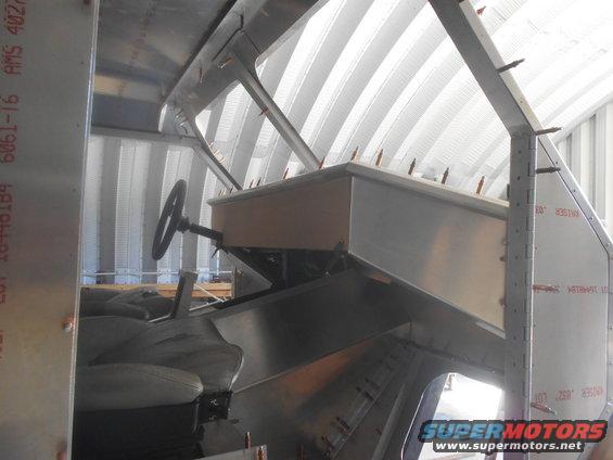 Interior view of a vehicle build, showing seats, steering wheel, and unfinished metal construction