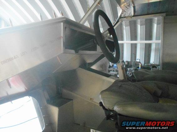 Vehicle interior with metal dashboard, steering wheel, and seat. Text visible on dashboard