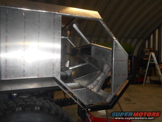 Aluminum panels being riveted to a frame, showing interior structure and a large tire