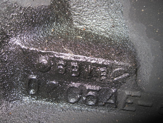 Close-up of a cast iron engine part with raised numbers: C5BA and 12A054E