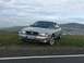 2003 Mercury Marauder - A silver 2003 Mercury Marauder is parked on a grassy overlook, with a town and hills visible in the distance.