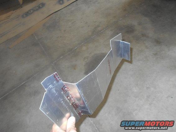 Metal bracket with red markings, held by a hand against a concrete floor