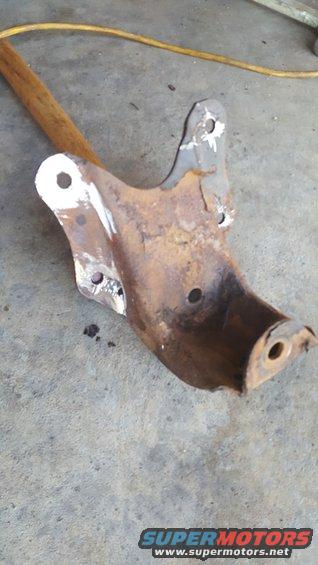 Rusty metal suspension part with a wooden handle resting on concrete