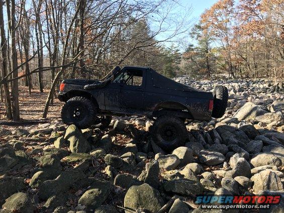 Black SUV with snorkel and spare tire on rocks. Modified for off-roading