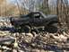 1989 Ford Bronco - This black SUV is navigating a rocky trail through a forest.