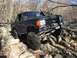 1989 Ford Bronco - A black Ford Bronco is shown off-roading through a challenging rocky landscape.