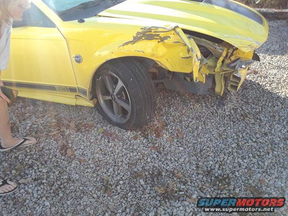 Yellow 2003 Ford Mustang with significant damage to the front fender and bumper